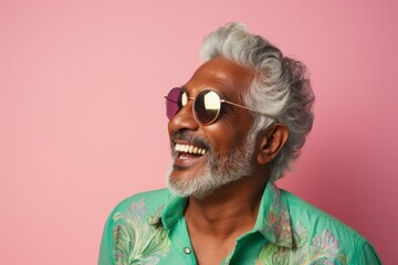 Portrait of a joyful indian man in his 60s wearing a trendy sunglasses against a pastel or soft...