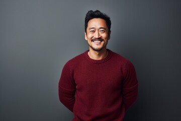 Portrait of a cheerful asian man in his 30s dressed in a warm wool sweater against a minimalist or empty room background. AI Generation - obrazy, fototapety, plakaty