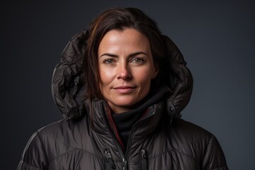 Portrait of a glad woman in her 40s donning a durable down jacket against a minimalist or empty room background. AI Generation