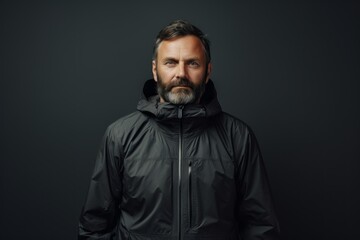 Portrait of a glad man in his 40s wearing a functional windbreaker against a minimalist or empty room background. AI Generation