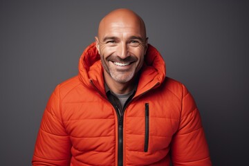 Portrait of a cheerful man in his 40s sporting a quilted insulated jacket against a minimalist or empty room background. AI Generation