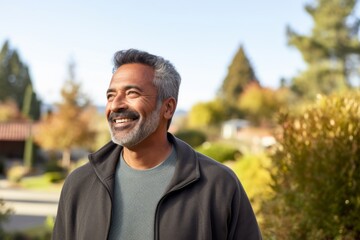 Obraz premium Portrait of a glad indian man in his 50s wearing a cozy sweater against a minimalist or empty room background. AI Generation