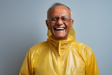 Portrait of a happy indian man in his 80s wearing a windproof softshell against a minimalist or empty room background. AI Generation