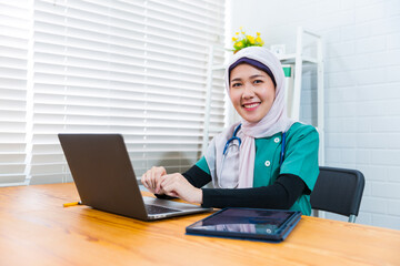 Female Muslim Islamic doctor working in hospital modern office exam checkup clinic room, wearing...