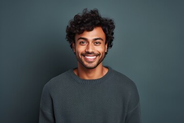 Fototapeta na wymiar Portrait of a cheerful indian man in his 20s wearing a cozy sweater against a minimalist or empty room background. AI Generation