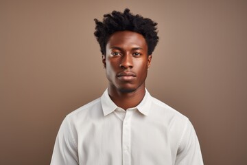 Portrait of a tender afro-american man in his 20s wearing a simple cotton shirt against a minimalist or empty room background. AI Generation