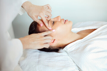 Fototapeta na wymiar Cosmetician applying eye patches on face of woman