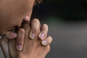 A man praying and close your eyes in praying. Prayer to pray. A young man is holding palms by his lips, whispering a prayer, and asking.