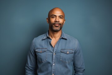 Fototapeta premium Portrait of a content afro-american man in his 40s sporting a versatile denim shirt against a solid color backdrop. AI Generation