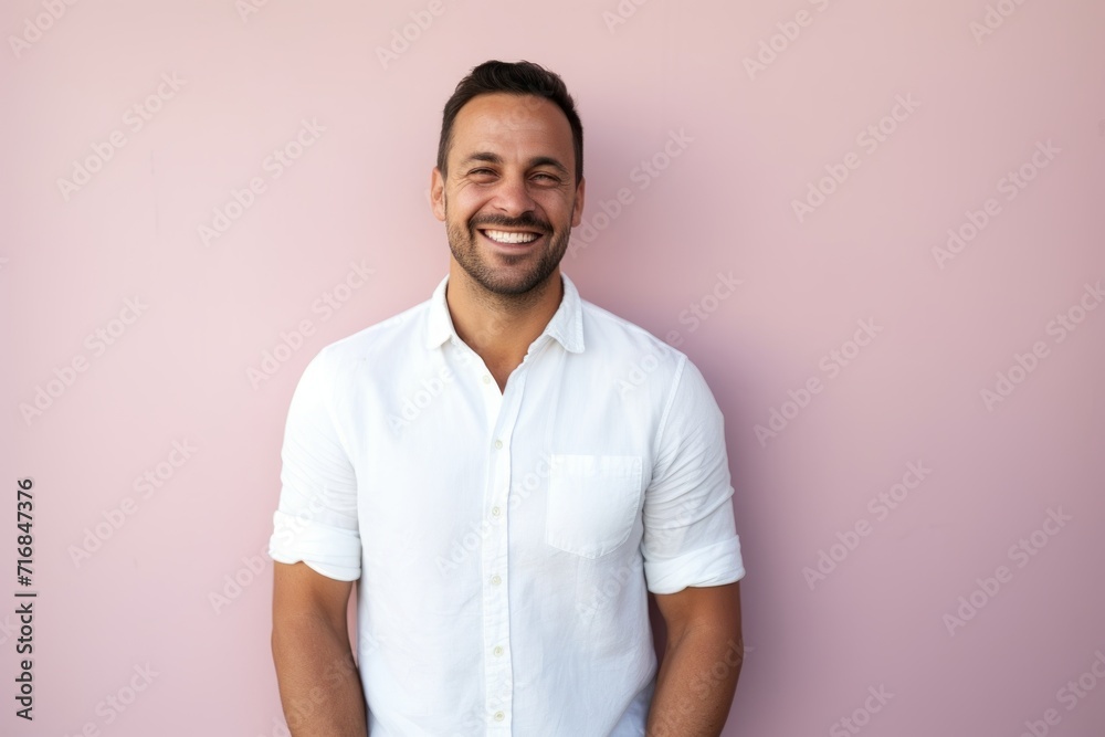 Wall mural Portrait of a cheerful man in his 30s wearing a simple cotton shirt against a solid pastel color wall. AI Generation