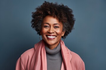Portrait of a grinning afro-american woman in her 50s dressed in a water-resistant gilet against a...