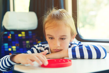 Cute child playing popit toy during travelling by train. Entertainment for young passenger.