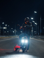 A man on a powerful electric scooter on a night road. Modern urban transport. Night trip around the city