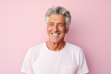 Portrait of a cheerful man in his 60s wearing a simple cotton shirt against a solid pastel color...