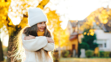 Happy girl walking in autumn park. Little girl wearing warm knitted sweater.