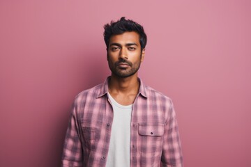 Portrait of a content indian man in his 20s dressed in a relaxed flannel shirt against a solid pastel color wall. AI Generation
