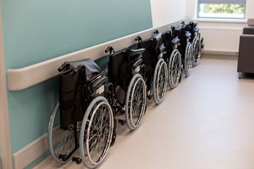 A row of empty folded wheelchairs along a corridor of clinic