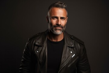 Fototapeta premium Portrait of a blissful man in his 40s sporting a classic leather jacket against a blank studio backdrop. AI Generation
