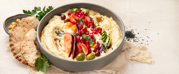 Hummus. Large bowl of homemade hummus garnished with chickpeas, vegetables and olive oil. Middle east food.