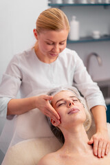 Fototapeta na wymiar beautician rubs the serum into the client's face in the salon with massaging movements