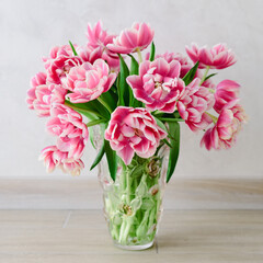 Bouquet of pink tulips into vase on wooden background. Anniversary celebration concept. Copy space. Front view