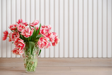 Bouquet of pink tulips into vase on wooden background. Anniversary celebration concept. Copy space. Front view