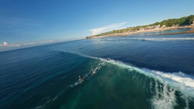 A surfer riding a spiralling clear ocean wave and wipeout at Uluwatu Bali, Indonesia. Aerial fast FPV drone footage