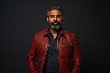 Portrait of a blissful indian man in his 40s wearing a trendy bomber jacket against a bare monochromatic room. AI Generation