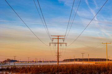 Mehrere Stromtrasse auf schneebedeckten Felder während eines Sonnenaufgang mit hohen Minusgraden. 