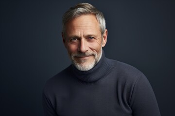 Obraz premium Portrait of a happy man in his 50s wearing a classic turtleneck sweater against a bare monochromatic room. AI Generation