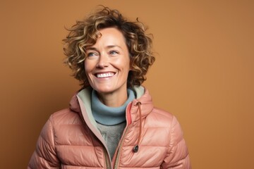 Portrait of a joyful woman in her 40s sporting a quilted insulated jacket against a plain cyclorama studio wall. AI Generation - obrazy, fototapety, plakaty