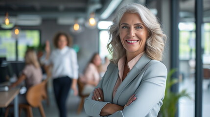 Smiling middle aged beautiful female business person in front of cheerful co-workers in office