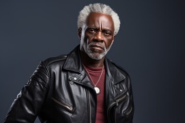 Obraz premium Portrait of a content afro-american man in his 60s sporting a classic leather jacket against a plain cyclorama studio wall. AI Generation