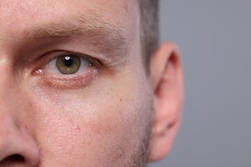 Obraz premium Closeup view of man with beautiful eyes on grey background, space for text