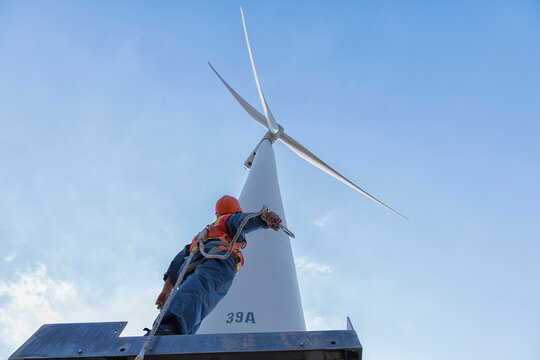 wind turbine in the wind. worker in Personal Protective Equipment work with wind turbine farm.  people in Safety Harness work on wind mill.