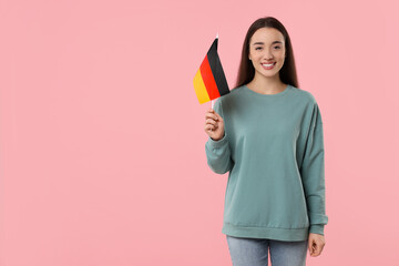 Young woman holding flag of Germany on pink background, space for text