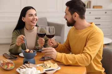 Affectionate couple enjoying chocolate fondue during romantic date at home