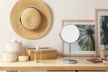 Mirror, perfume and makeup products on wooden dressing table