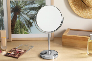 Mirror, pictures and makeup products on wooden dressing table