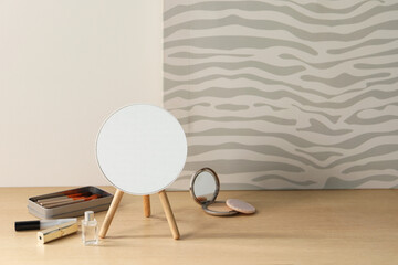 Mirror, makeup products and perfume on wooden dressing table in room. Space for text