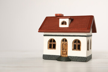 Mortgage concept. House model on white wooden table, space for text