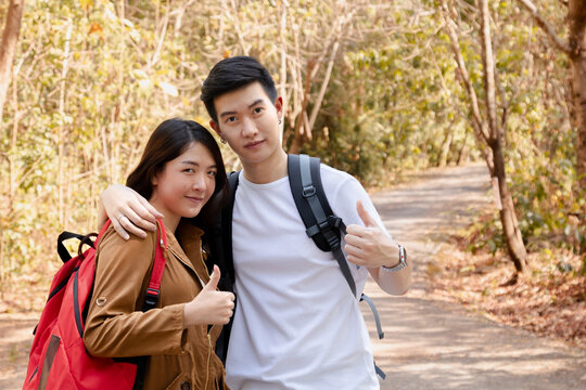 Asian lovers male and female walking hiking together in park happy exercise outdoors carefree activity, happy couple traveler one day backpack trip travel in summer day vacation bonding relationship