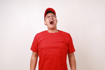 Frustrated young asian courier standing while screaming against white background
