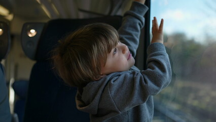 Child Playing with Train Blinds on European High-Speed Journey. Little boy passenger closes shades