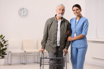 Smiling nurse supporting elderly patient in hospital, space for text