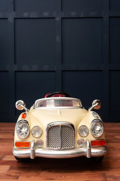 a classic plastic children's car on a dark blue wall background. a photo zone with a small car in a photo studio