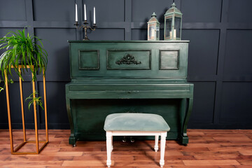 a dark green piano with a light chair against a dark blue wall. a ready-made decoration for a...