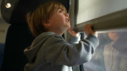 Child closing and opening train blinds during trip inside high-speed transportation in Europe....