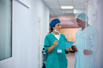 Female doctor communicating with black senior man who is recovering after surgery in hospital.