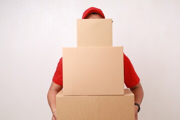Asian courier man in red standing with pile of cardboard box. Isolated on white